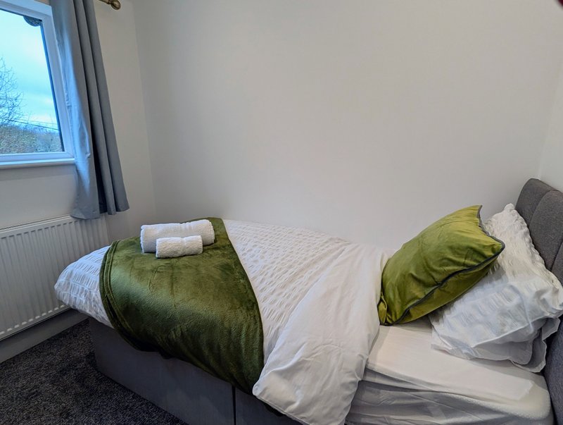 A cosy single bedroom with a comfortable bed and a chest of drawers for storage. The room is bright and simply furnished and the window provides plenty of natural light.