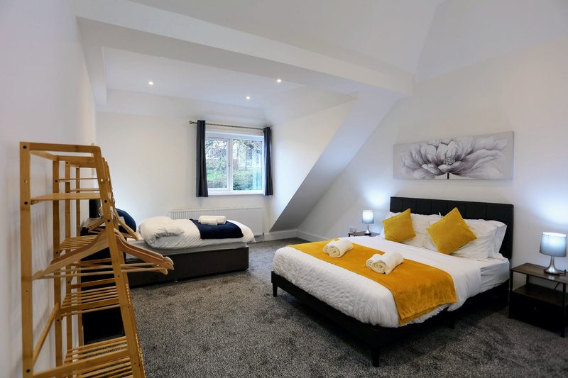 A spacious bedroom featuring a comfortable king-size bed alongside a separate single bed, making it ideal for groups. The room has plenty of space and ample storage for belongings.