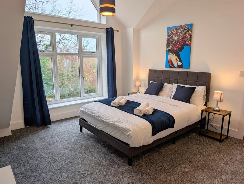 Generously sized king-size bedroom with a modern, comfortable feel and plenty of natural light from the large feature window.