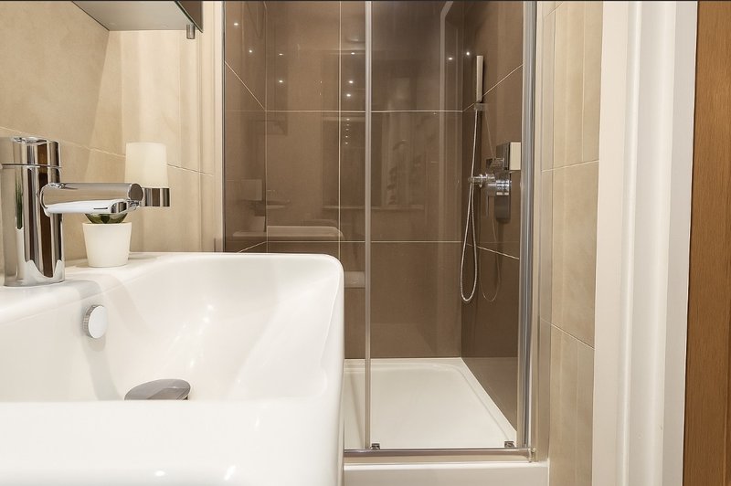 Modern bathroom with white sink, chrome tap, and glass-enclosed shower enclosure