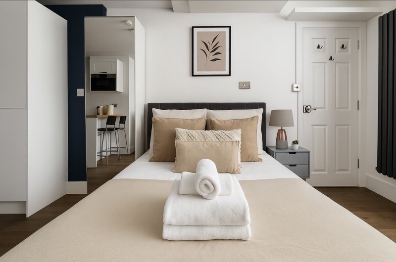 Modern bedroom with double bed, beige bedding, wall art, and en-suite access