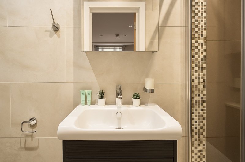 Modern bathroom with white pedestal sink, mirror cabinet, and decorative tile accents