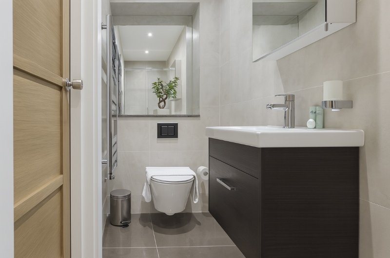 Modern bathroom with wall-mounted toilet, dark vanity unit, white sink and large mirror