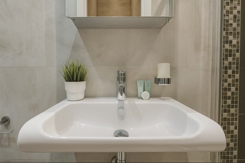 Modern bathroom sink with white basin, chrome faucet, mirror and decorative accessories