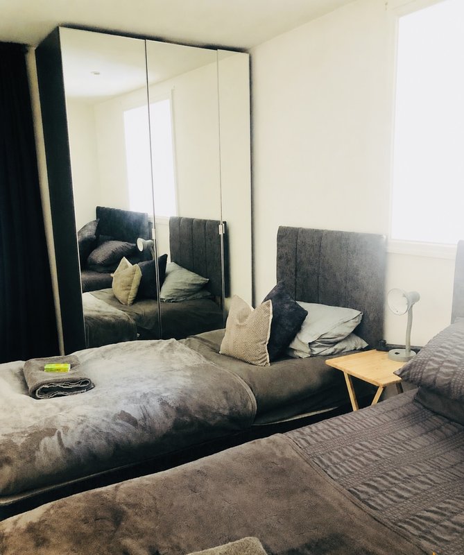 Bedroom with double bed, mirrored wardrobe, grey headboard and bedside table