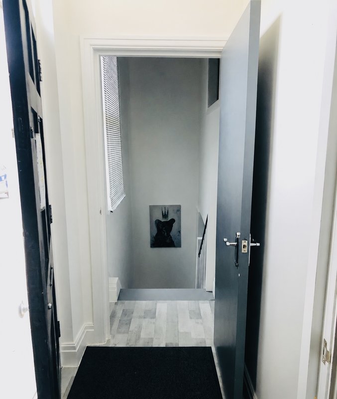 Narrow hallway with white walls, black door frame, and light wood-effect flooring