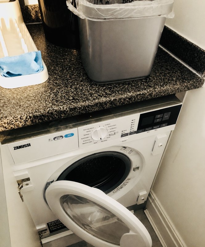 Utility room with washing machine, granite countertop, laundry basket and cleaning supplies