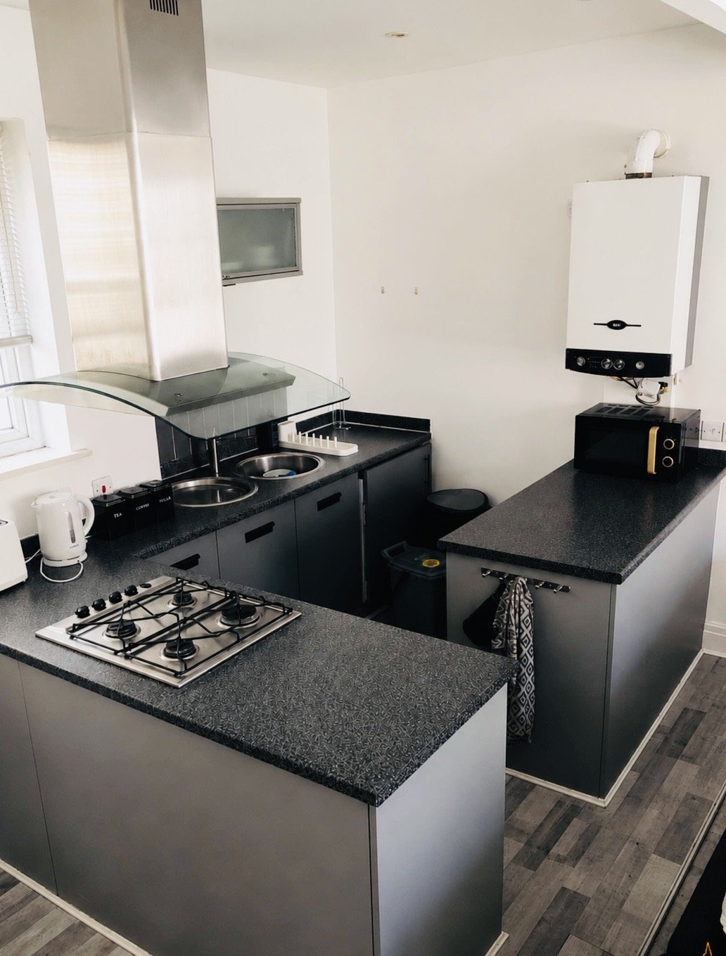 Modern kitchen with black cabinetry, gas hob, dark countertops and stainless steel appliances
