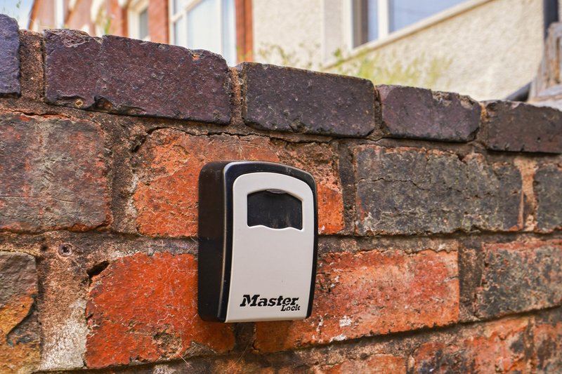 Brick exterior wall with mounted key storage box showing brand name