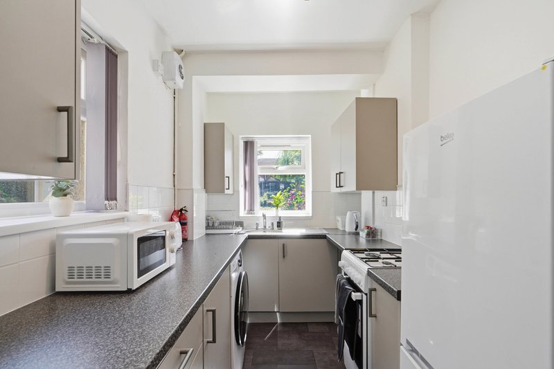 Modern kitchen with gray cabinetry, stainless steel appliances, and natural light from window