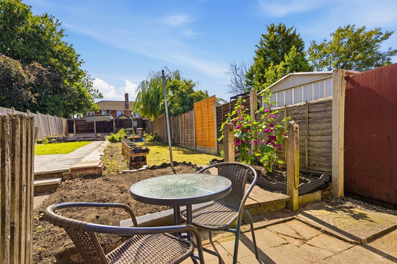 Outdoor garden patio with round table, chairs, and flowering plants against wooden fences