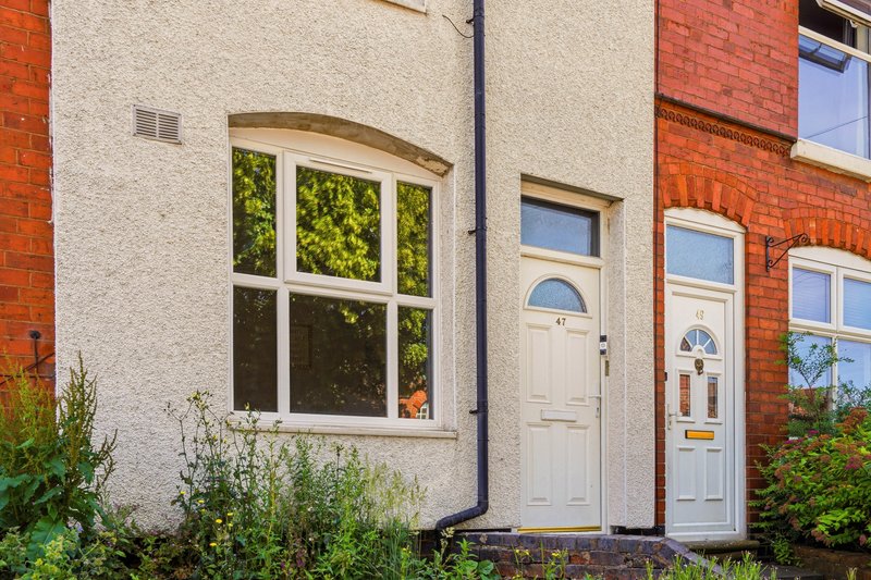 Exterior view of brick terraced house with cream door and large window