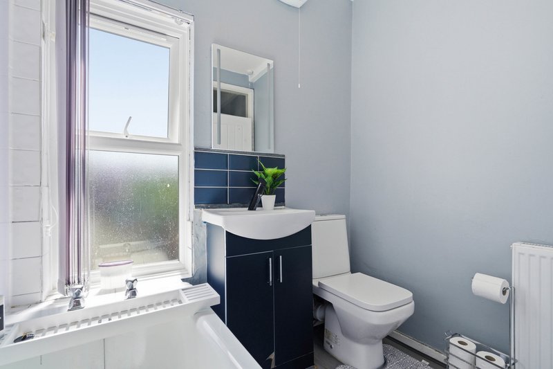 Modern bathroom with black vanity, white toilet, blue tile backsplash and window
