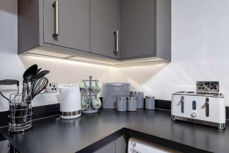 Modern kitchen counter with gray cabinetry, under-cabinet lighting, and countertop appliances