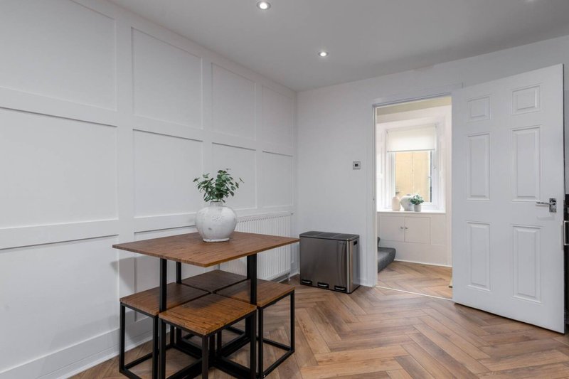 Modern dining area with wooden table, benches, potted plant and white panelled walls