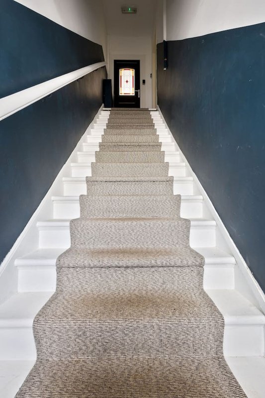 Long staircase with beige carpet, white risers, dark blue walls and white trim