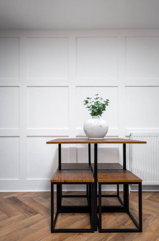 Modern living room with geometric shelving unit, potted plant in white vase, herringbone wooden floor