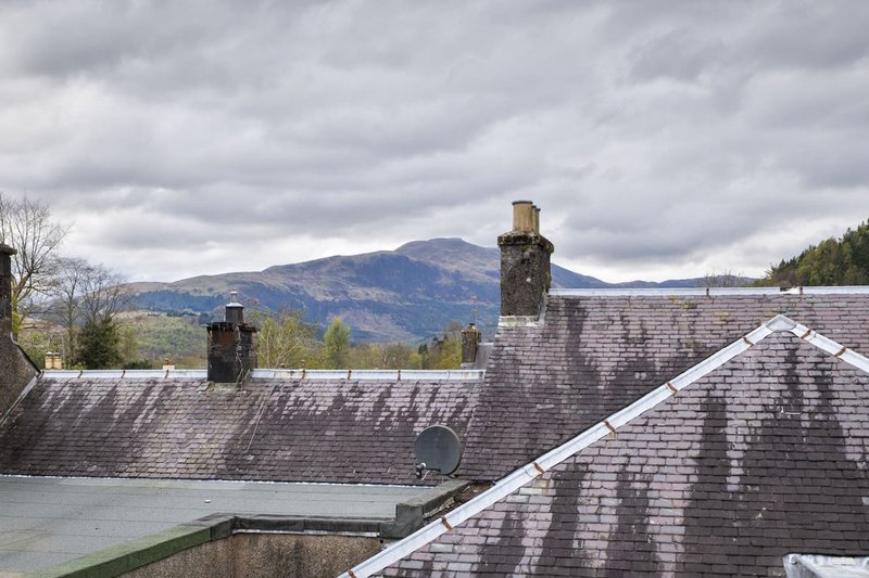 Stone cottage roof with chimneys overlooking mountains and countryside