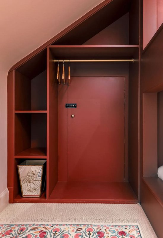 Red built-in wardrobe with shelving, hanging rail, and patterned rug flooring