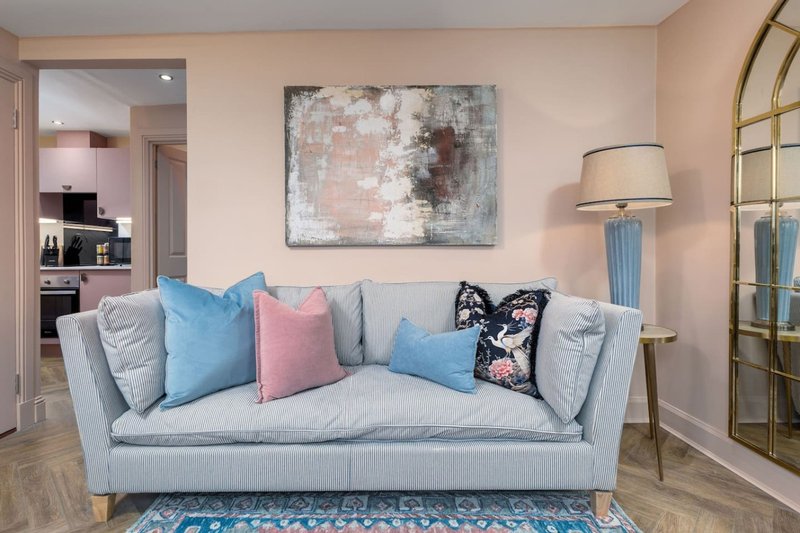 Light gray upholstered sofa with colorful cushions in modern living room with artwork and lamp