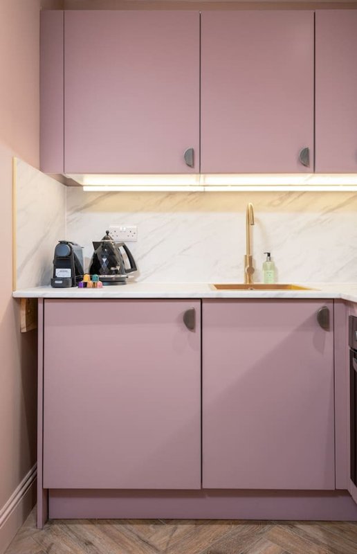 Modern kitchen with mauve cabinetry, marble countertop, and stainless steel fixtures