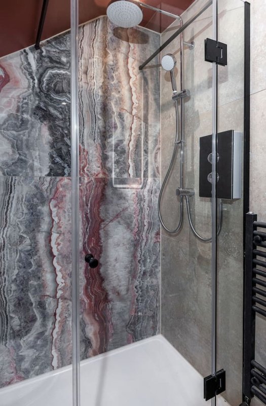 Modern bathroom shower enclosure with marble-effect tiled walls and rainfall showerhead