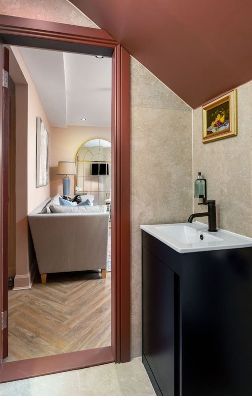 Bathroom with black vanity sink, wallpapered walls, and open doorway to bedroom beyond