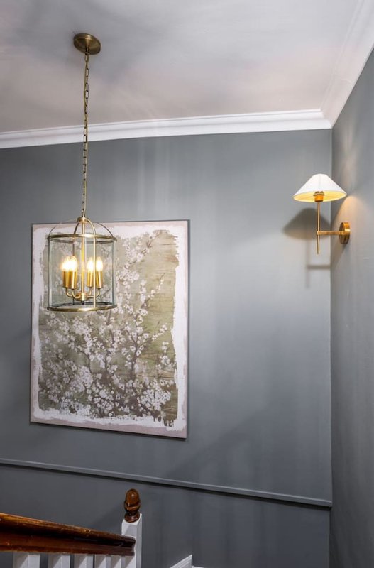 Modern hallway with gray walls, brass pendant light, wall sconce, and framed floral artwork