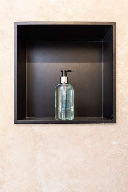 Built-in bathroom niche with glass soap dispenser bottle on shelf
