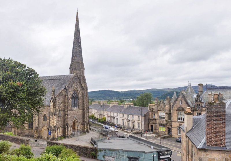 Elevated view of historic stone church with spire overlooking town street and period buildings