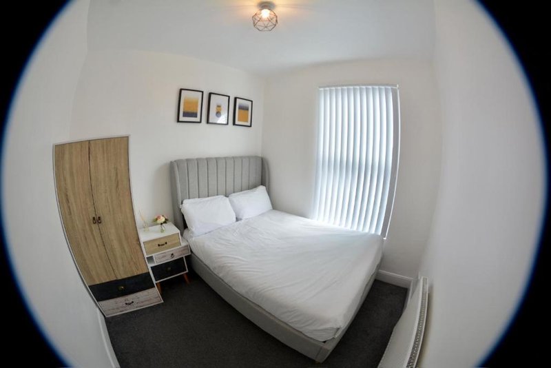 Bedroom with double bed, wooden wardrobe, bedside table and vertical blinds