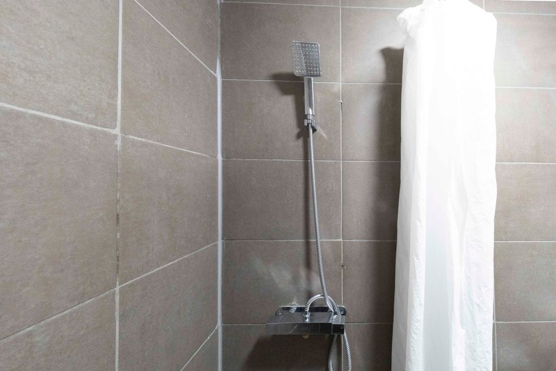 Modern bathroom shower cubicle with gray tile walls, rainfall showerhead and white towel