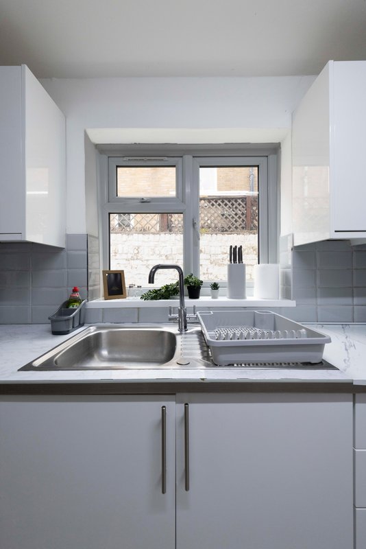 Modern kitchen with white cabinets, stainless steel sink, and window over countertop