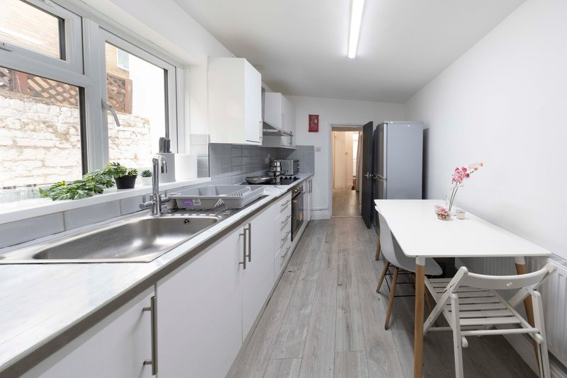 Modern kitchen with white cabinetry, stainless steel sink, dining table and chairs