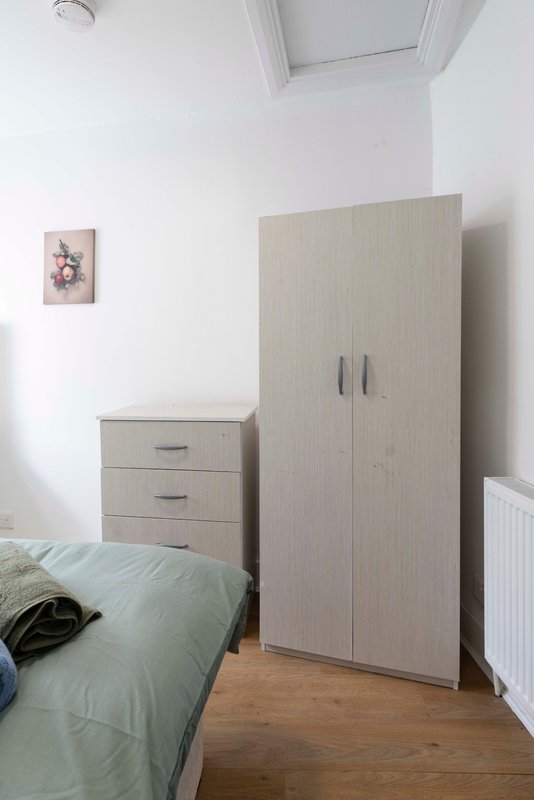 Bedroom with single bed, wooden wardrobe, bedside drawers and small wall art