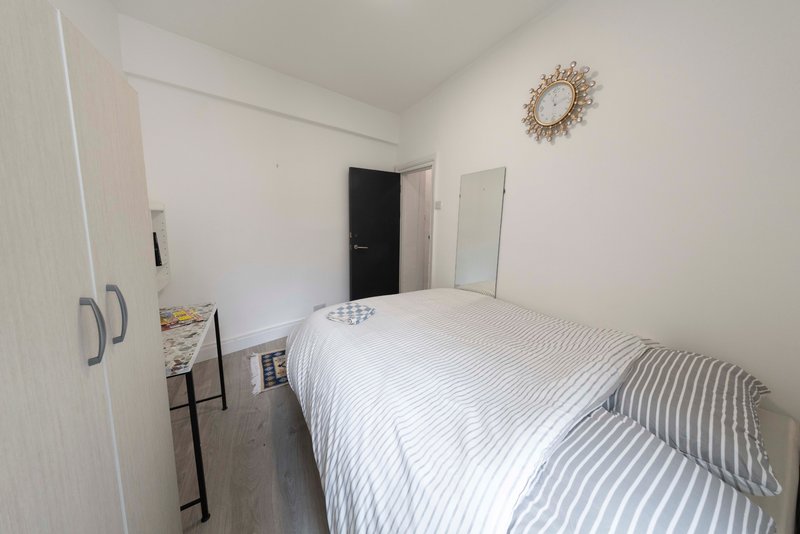 Bright bedroom with single bed, striped bedding, wardrobe, and decorative wall mirror