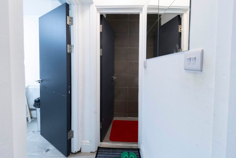 Hallway with blue door, white walls, red doormat, and bathroom entrance