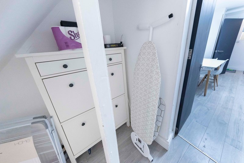 Attic hallway with white storage drawers, ironing board, and access to bedrooms