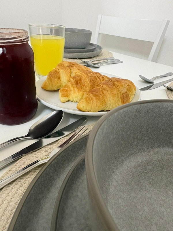 Breakfast table with croissants, orange juice, coffee and place settings
