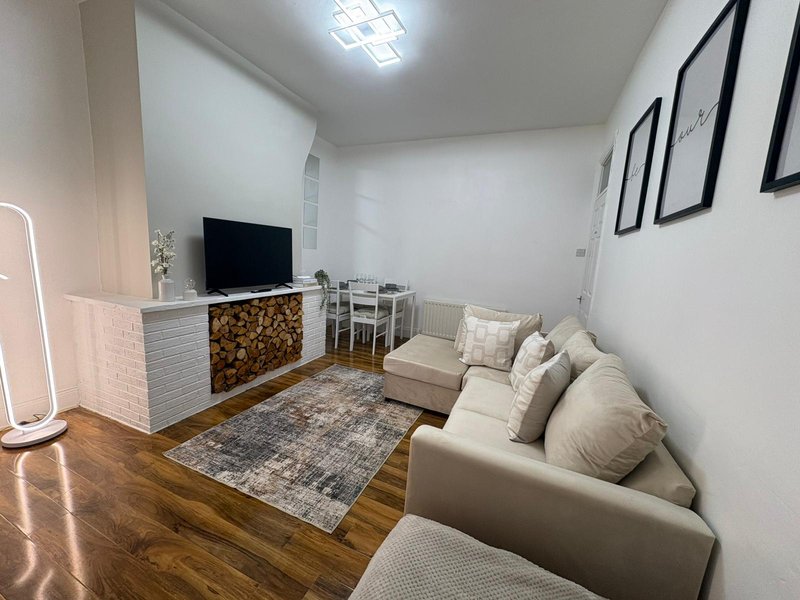 Modern living room with cream sofa, TV unit, wooden floor and framed wall art