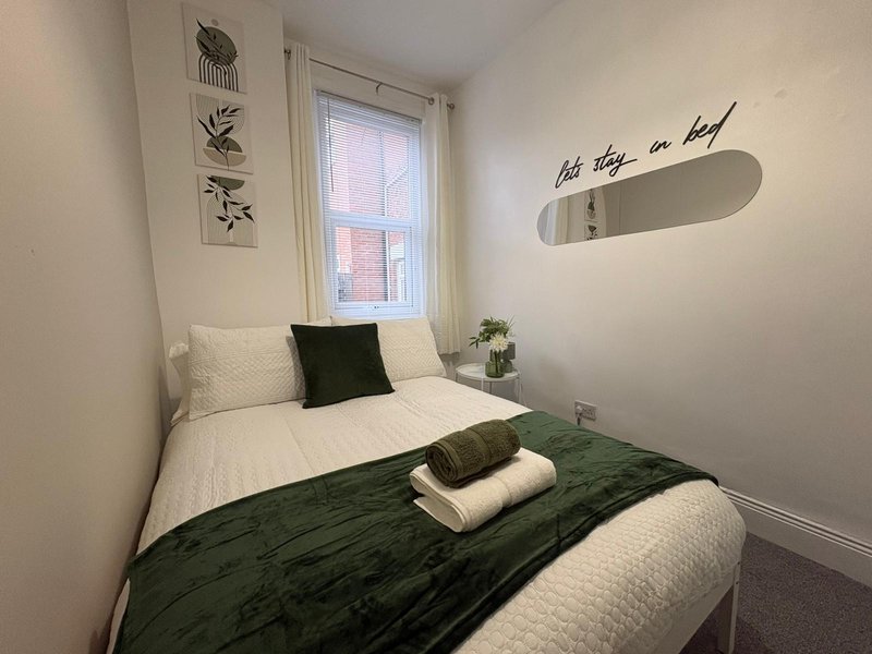 Compact bedroom with two single beds, window, wall art and mirror decoration