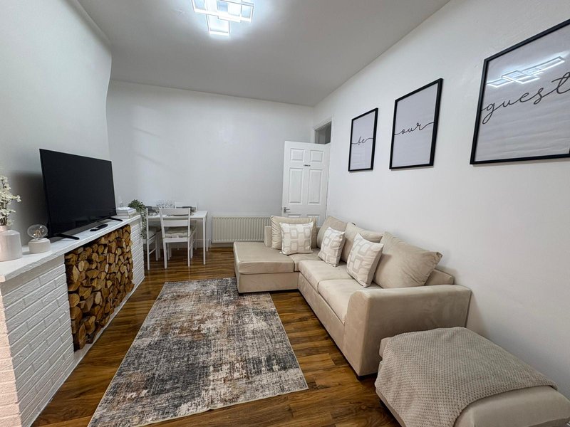 Modern living room with beige sofa, TV stand, decorative wall frames and wooden flooring