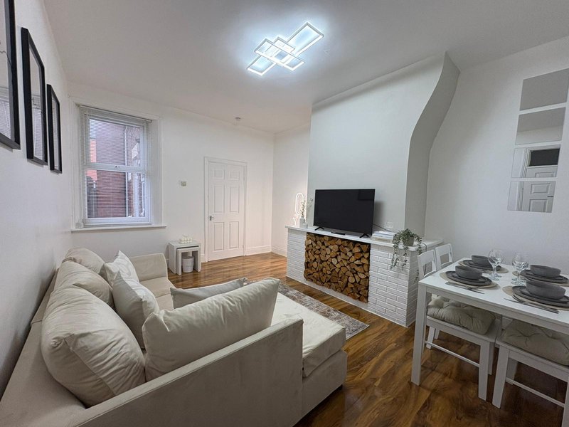 Bright living room with cream sofa, TV on fireplace, wooden flooring and dining table