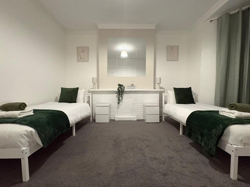 Twin bedroom with two single beds, shared vanity mirror, dark green cushions and curtains