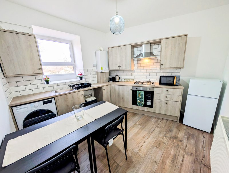 Modern kitchen with wooden cabinets, white appliances, dining table and pendant light