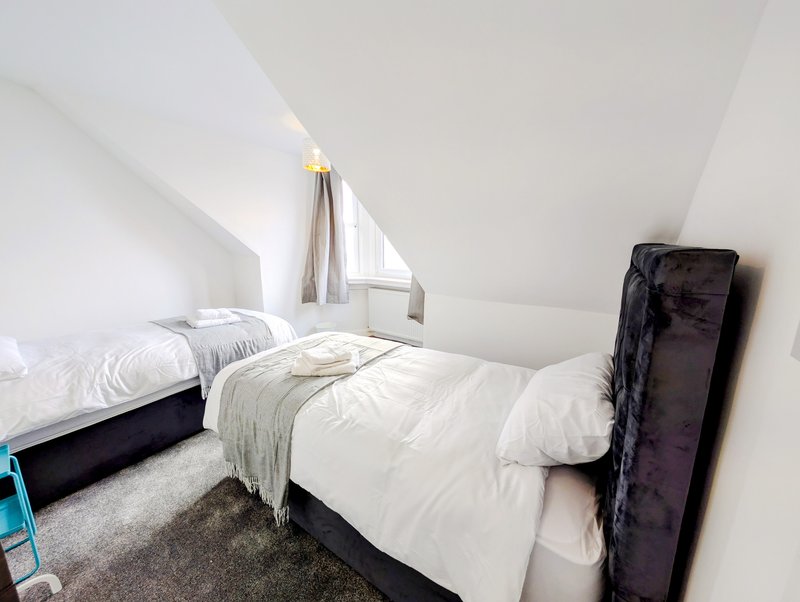 Bright attic bedroom with two single beds, white bedding, and sloped ceiling