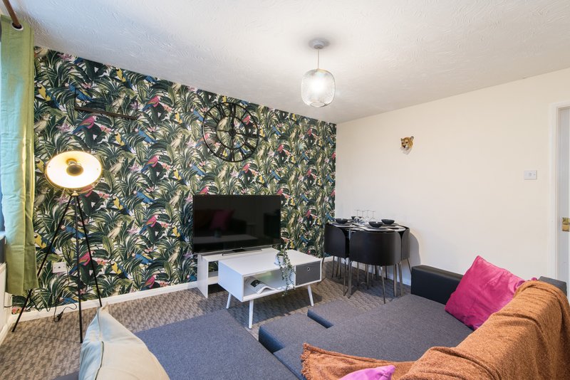 Living room with patterned feature wall, TV, white coffee table and brown sofa