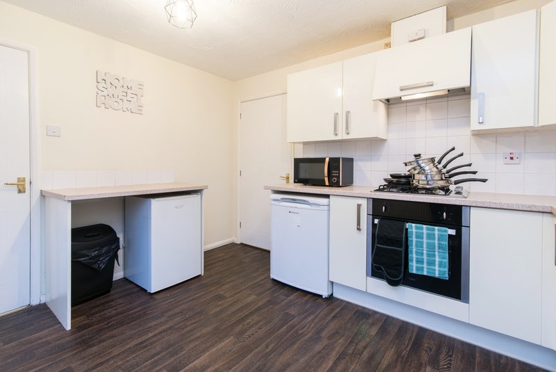 Modern kitchen with white cabinets, black countertop, integrated oven and microwave