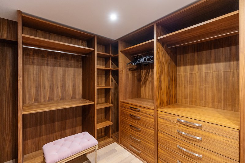 Luxury wooden walk-in wardrobe with built-in shelving, drawers and bench seating