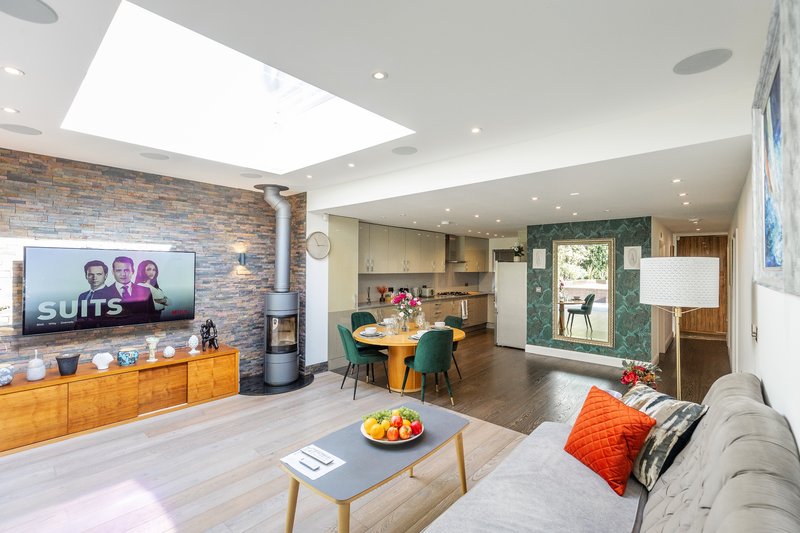 Open-plan living area with TV, kitchen, dining table, and seating with skylights